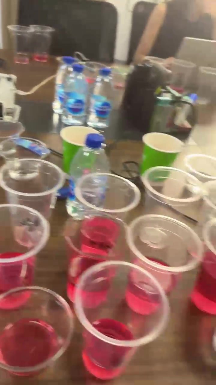 Rows of tasting cups filled with pink Jello samples on a table